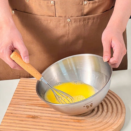 femme qui bat des oeufs dans saladier inox avec un fouet