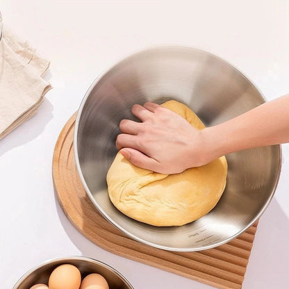 femme qui petrit de la pate dans saladier inox