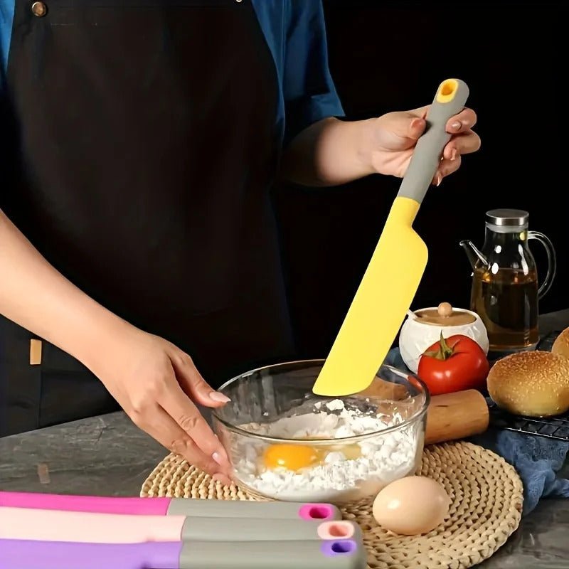 femme qui tient unespatule silicone jaune pour melanger dans un saladier farine oeuf