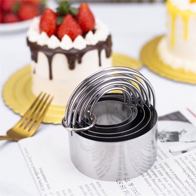 Plusieurs emporte pièce rond empilé devant un gâteau rond décoré. avec des fraises