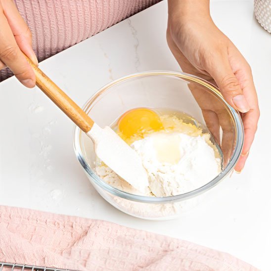 spatule en silicone qui melange de la farine a un oeuf
