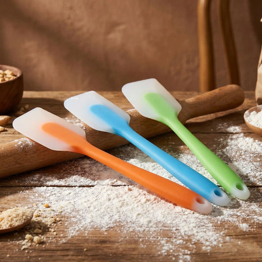 spatule silicone bleu vert orange sur plan travail  avec de la farine