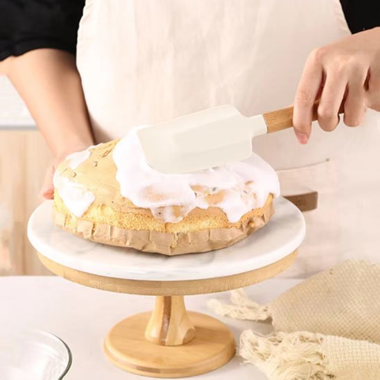 une femme lisse un gateau avec spatule en silicone